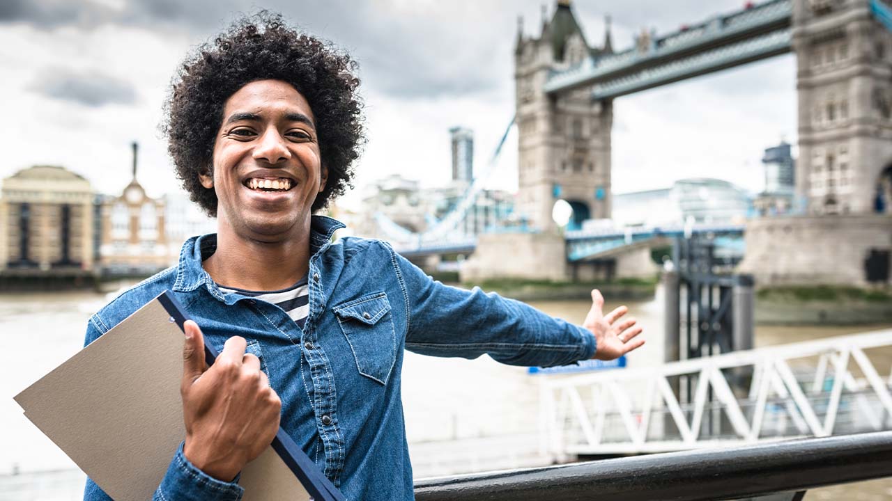 Jovem estudante em Londres, com fichários em uma mão enquanto mostra a vista da cidade